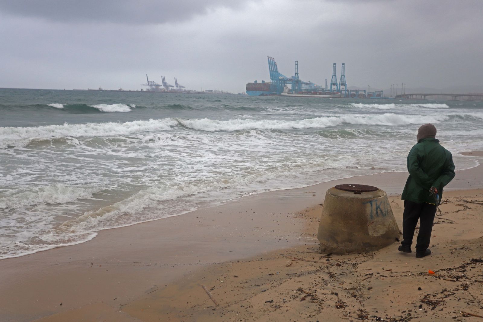 Una persona observa la Bahía de Algeciras desde la playa de El Rinconcillo con el Puerto al fondo.