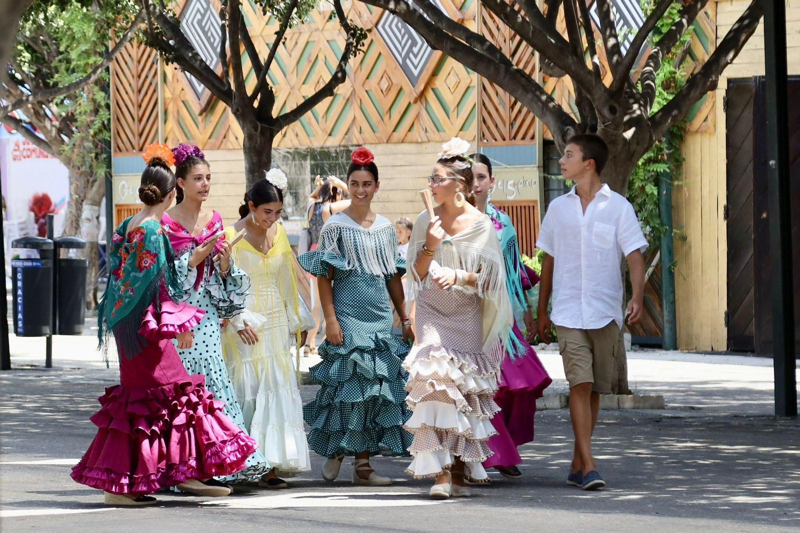 Un grupo de jóvenes se pasea por el Real con abanicos.