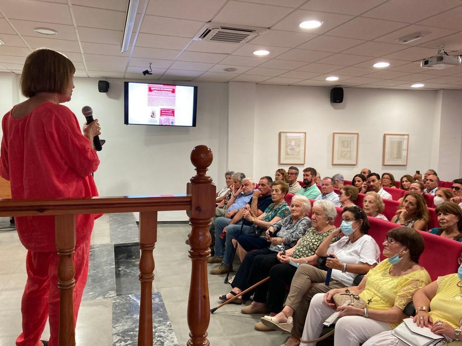 Quintina Falcón, hermana de Antonio, en la presentación del libro. Al fondo, los cuadros de Rolando y Paco Cuadrado.
