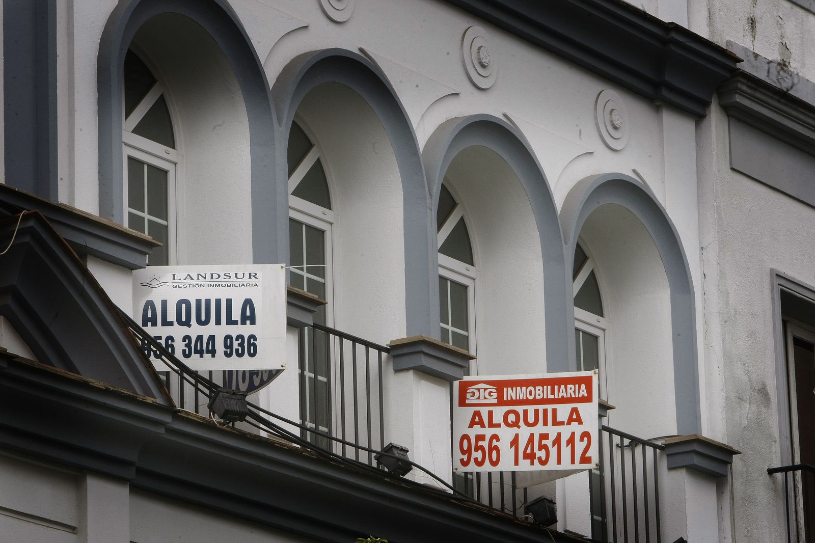 Retrospectiva de unos carteles de alquiler colgados en un balcón en una calle de Jerez.