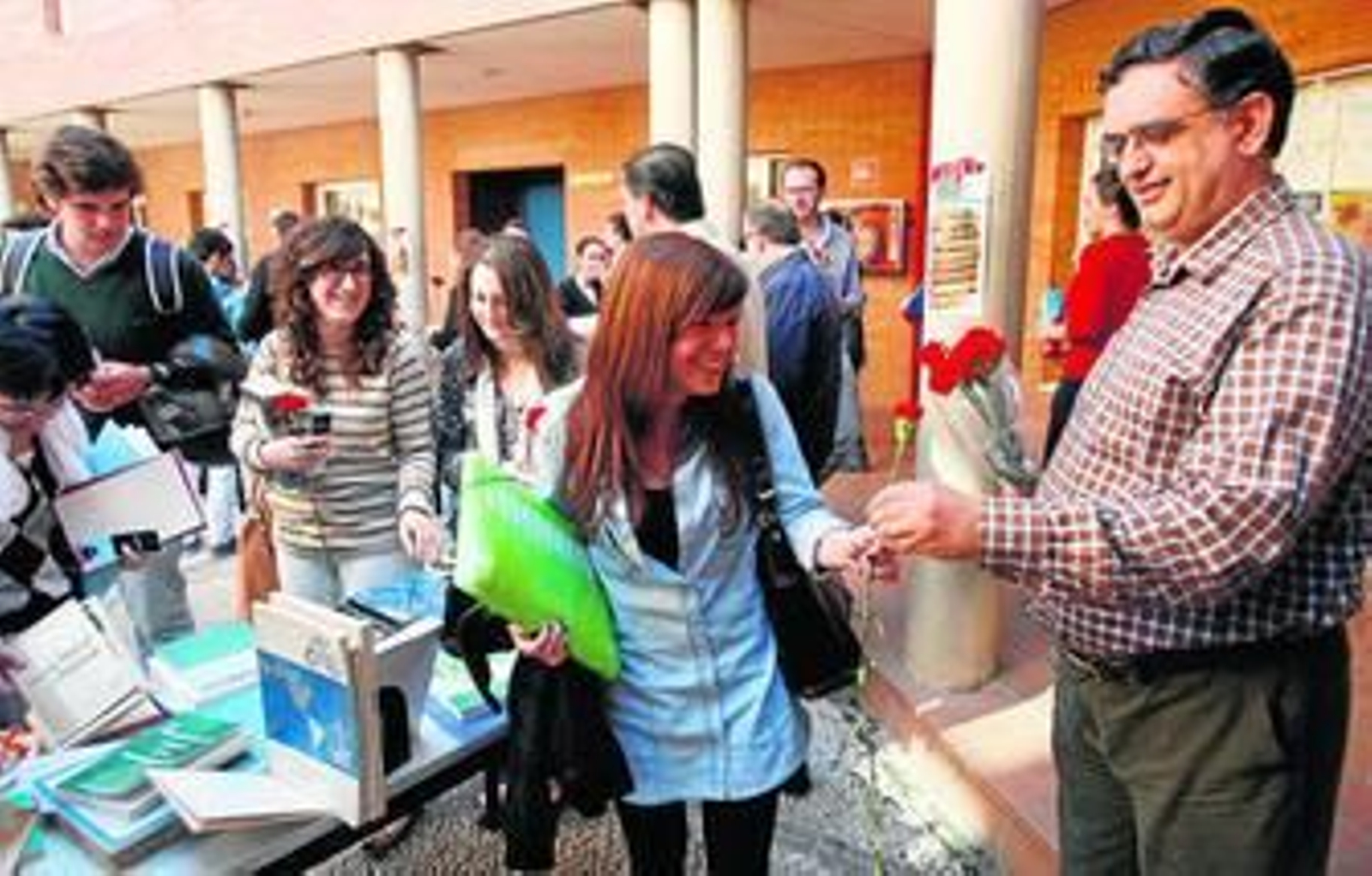 Un momento del reparto de claveles y libros en la Facultad de Derecho.