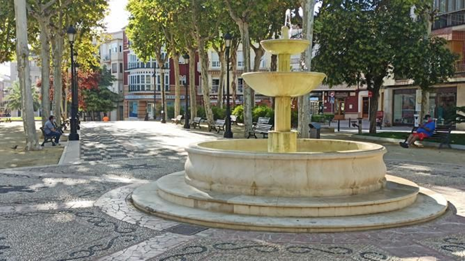 Dos personas portan la mascarilla mientras ocupan sendos bancos en el Paseo del Coso.