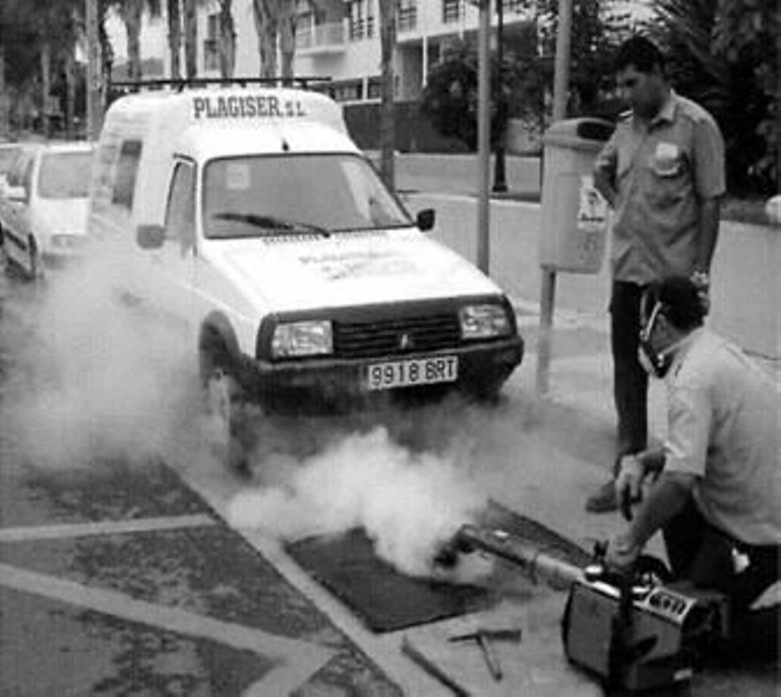 Empleados de una empresa de control de plagas fumigan una alcantarilla.