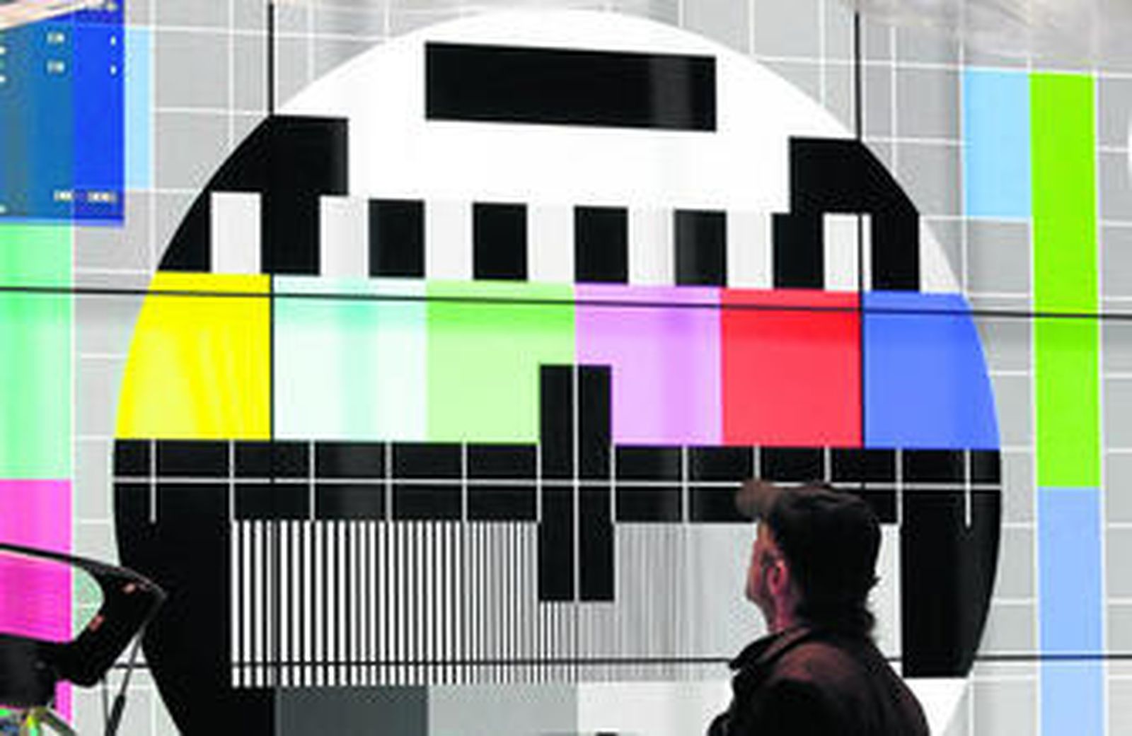 Un cliente de una feria tecnológica en Estados Unidos, ante una gigantesca pantalla con la carta de ajuste.