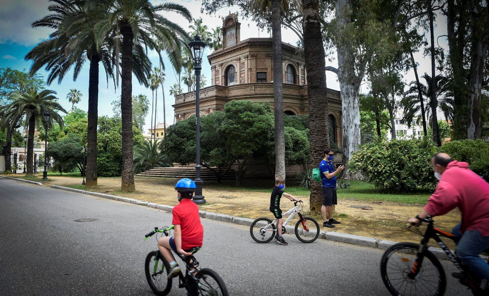 Una familia pasea en bici por el parque de María Luisa.