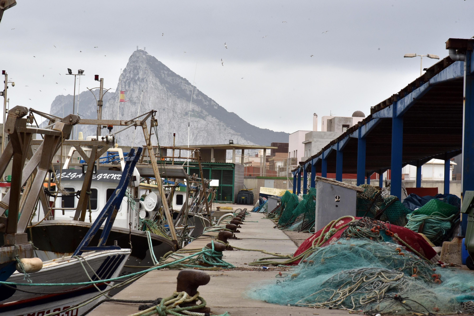 Pesqueros en el puerto de La Atunara y, al fondo, la silueta del peñón de Gibraltar.