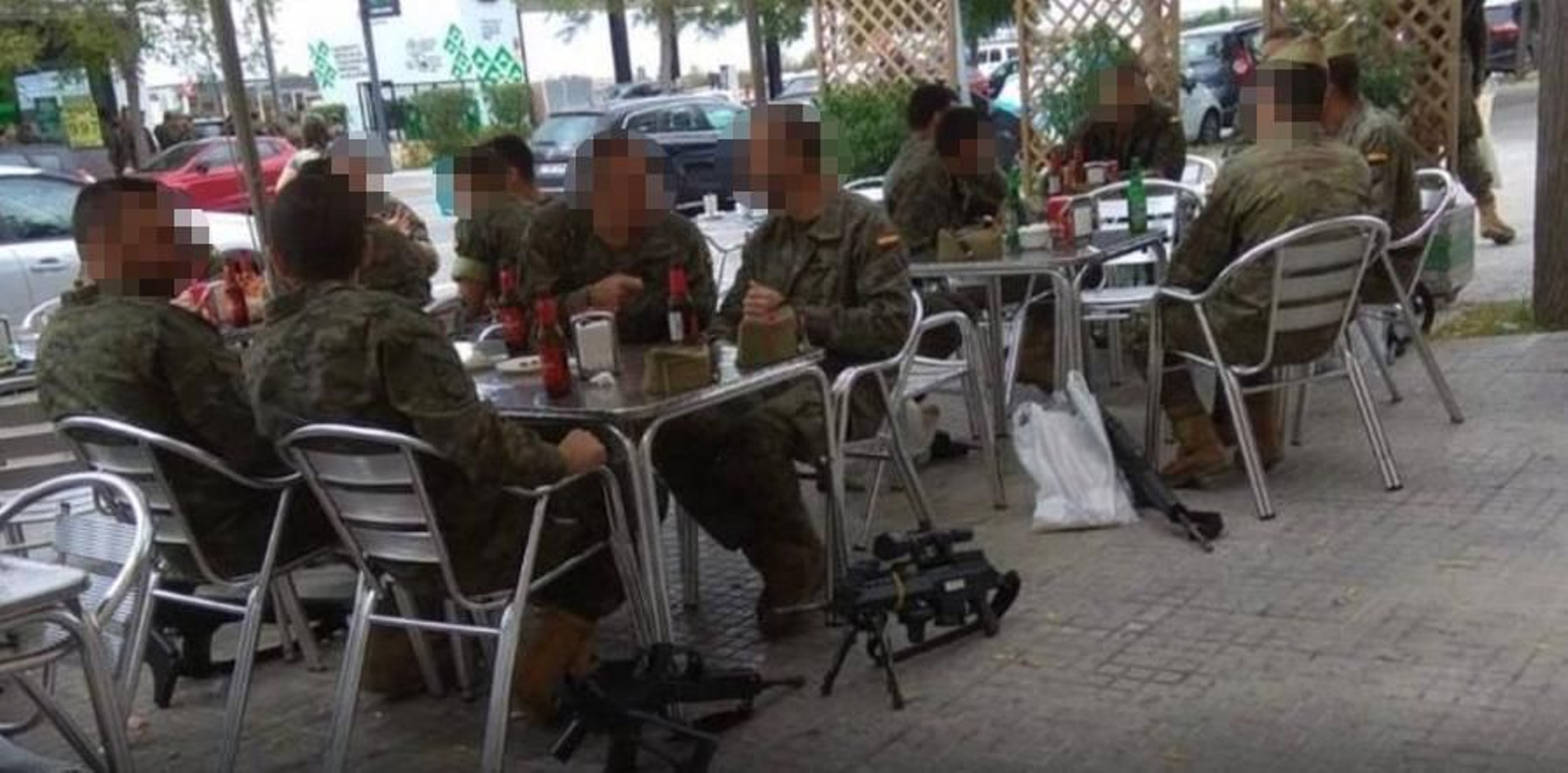 Los legionarios en la terraza de un bar con las armas en el suelo.