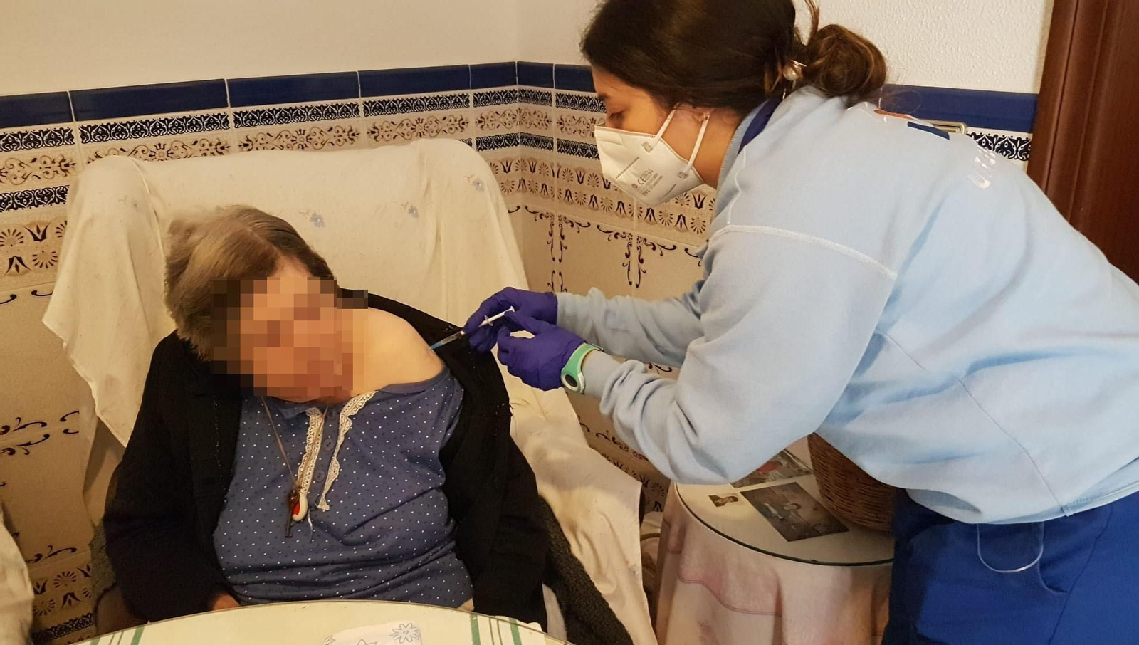 Una profesional sanitaria inyecta la dosis correspondiente a una persona en su domicilio.