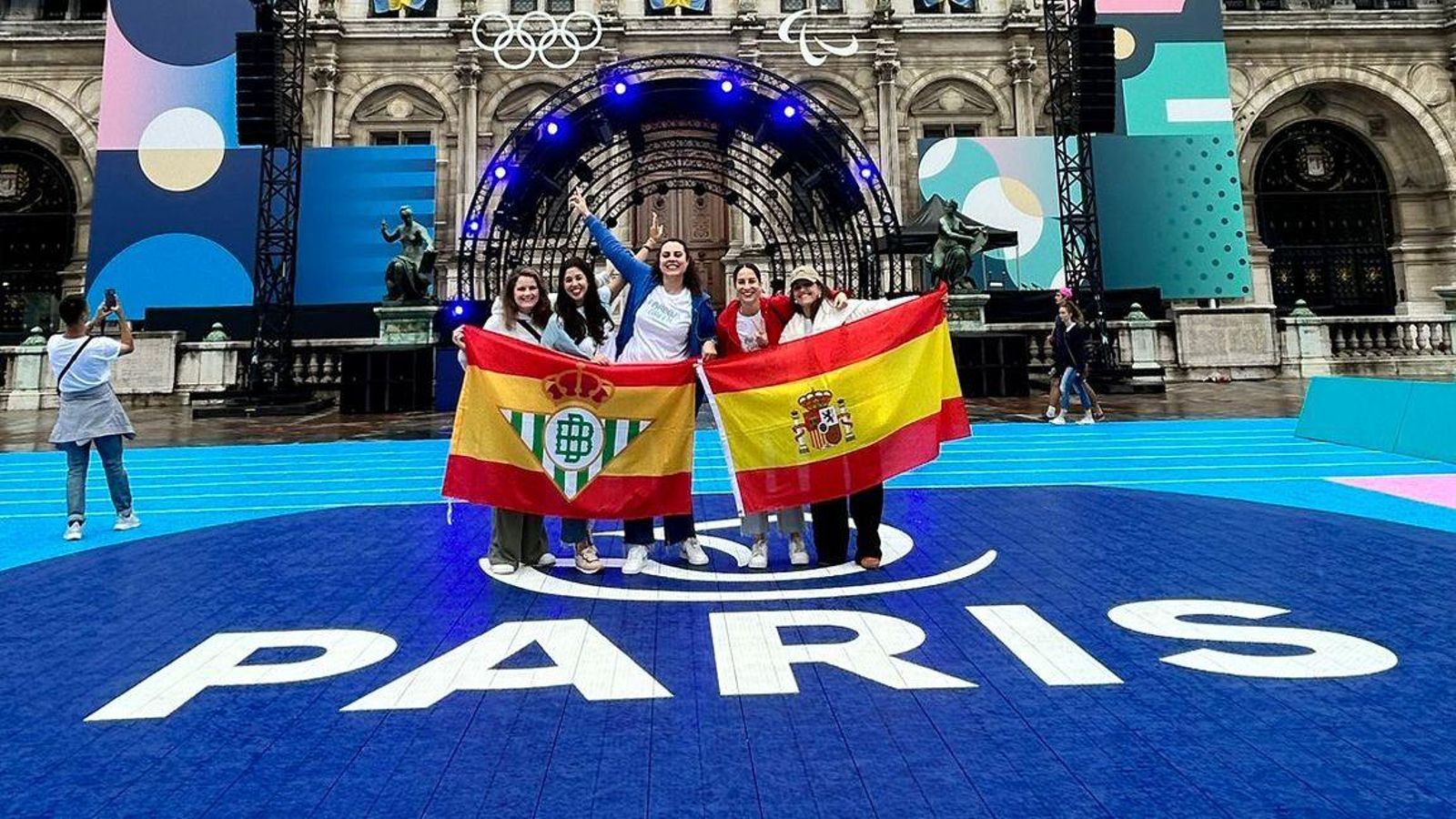 Rocío y sus amigas posan con la bandera del conjunto verdiblanco en París