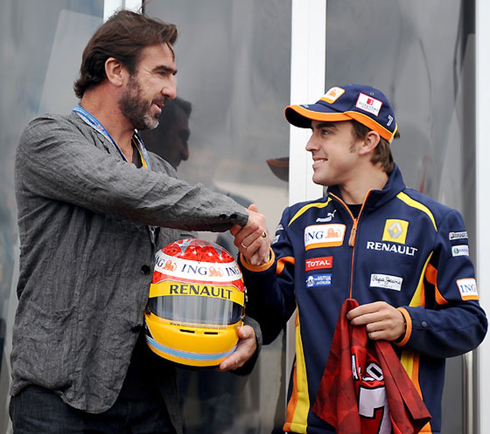 El ex futbolista Eric Cantona y el piloto de Renault Fernando Alonso intercambiaron regalos. El primero le dio al segundo una camiseta firmada y el asturiano un casco, también firmado.  Foto: Reuters / Afp Photo