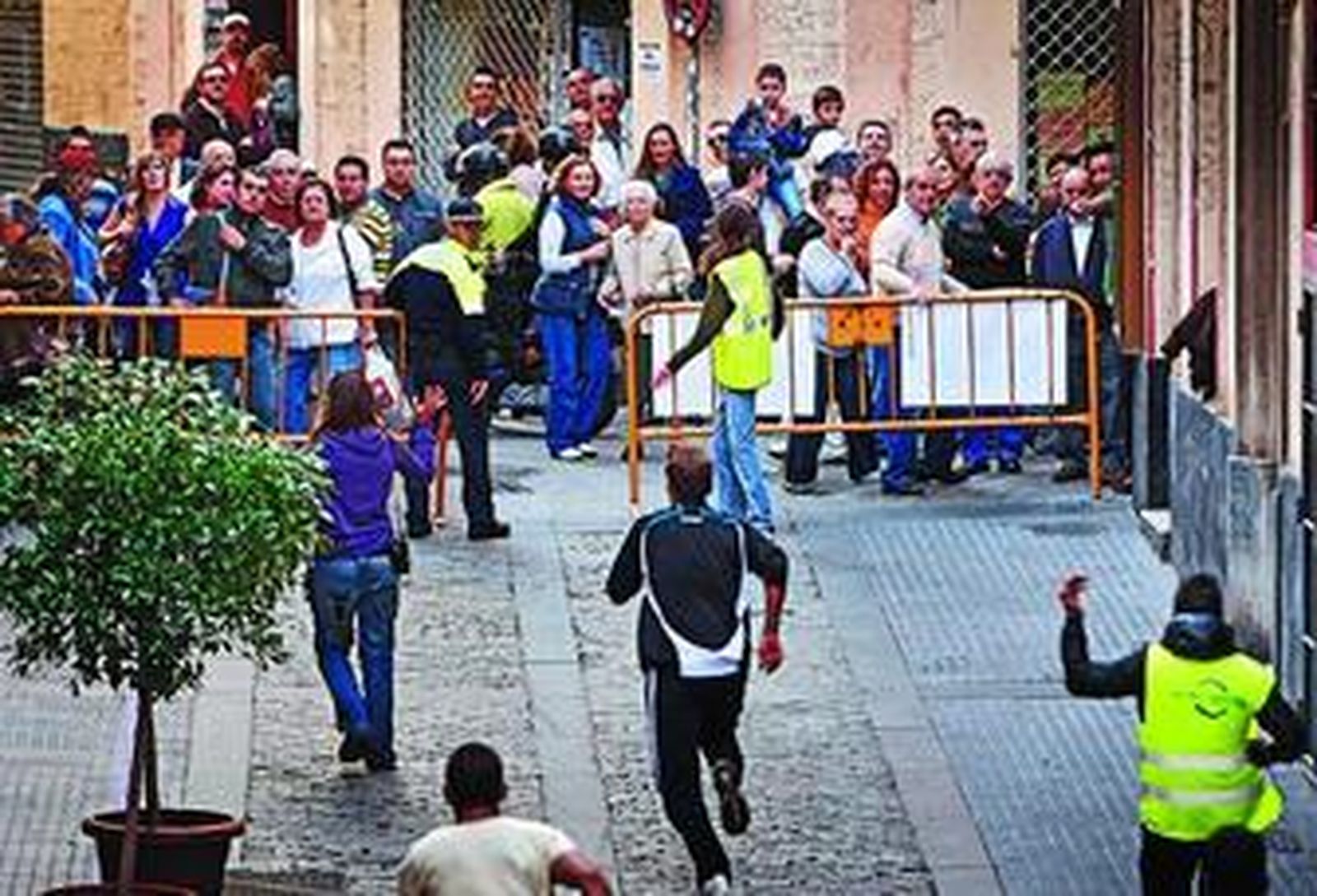 Efectivos de seguridad corren para avisar a los espectadores de que los toros están fuera de control.