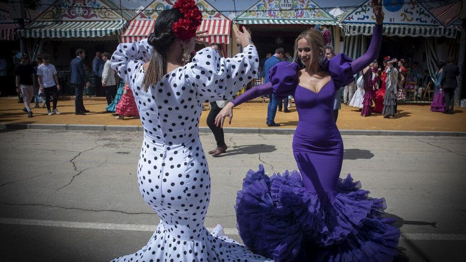 Dos mujeres vestidas de flamenca bailando sevillanas