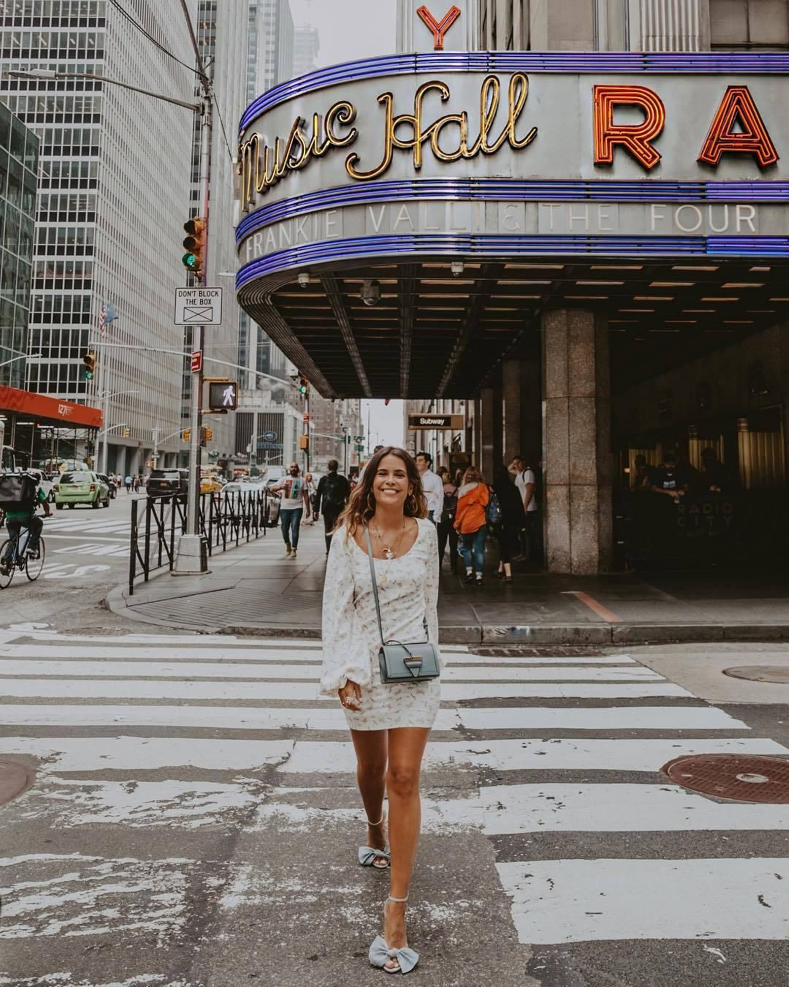 Sara de @collagevintage disfruta del inicio del otoño en las calles de Nueva York con un sencillo vestido blanco estampado con mangas abullonadas que accesoriza con tonos azules grisáceos. El calzado, unas preciosas sandalias de tacón con lazo oversize, es de Raye.