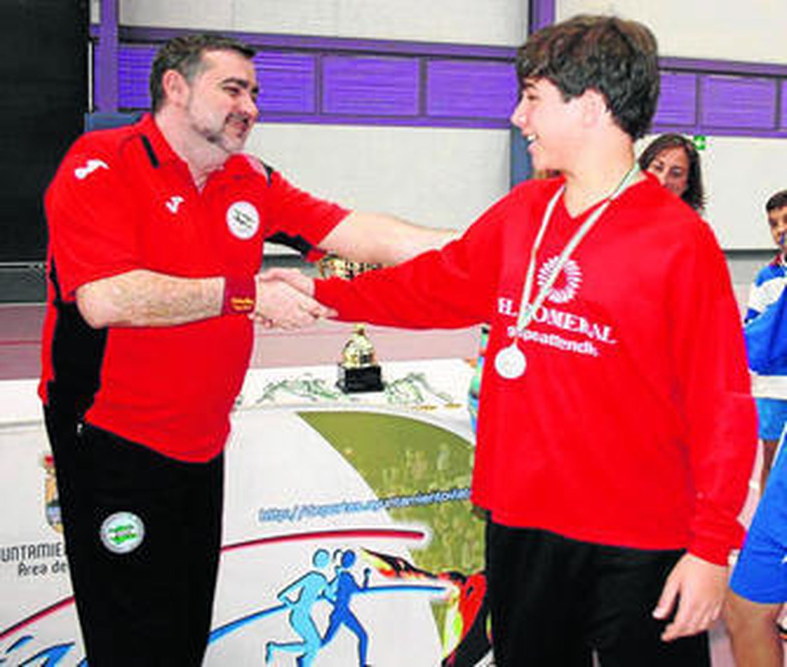 Juan Enrique entregando una medalla a un joven jugador.