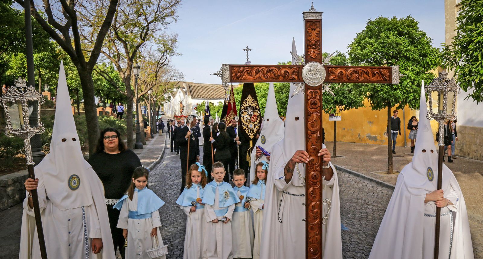 La cruz de guía abriendo el cortejo ayer, con los nazarenos vestidos de blanco impoluto y algunos pequeños acompañando a los hermanos del Resucitado.