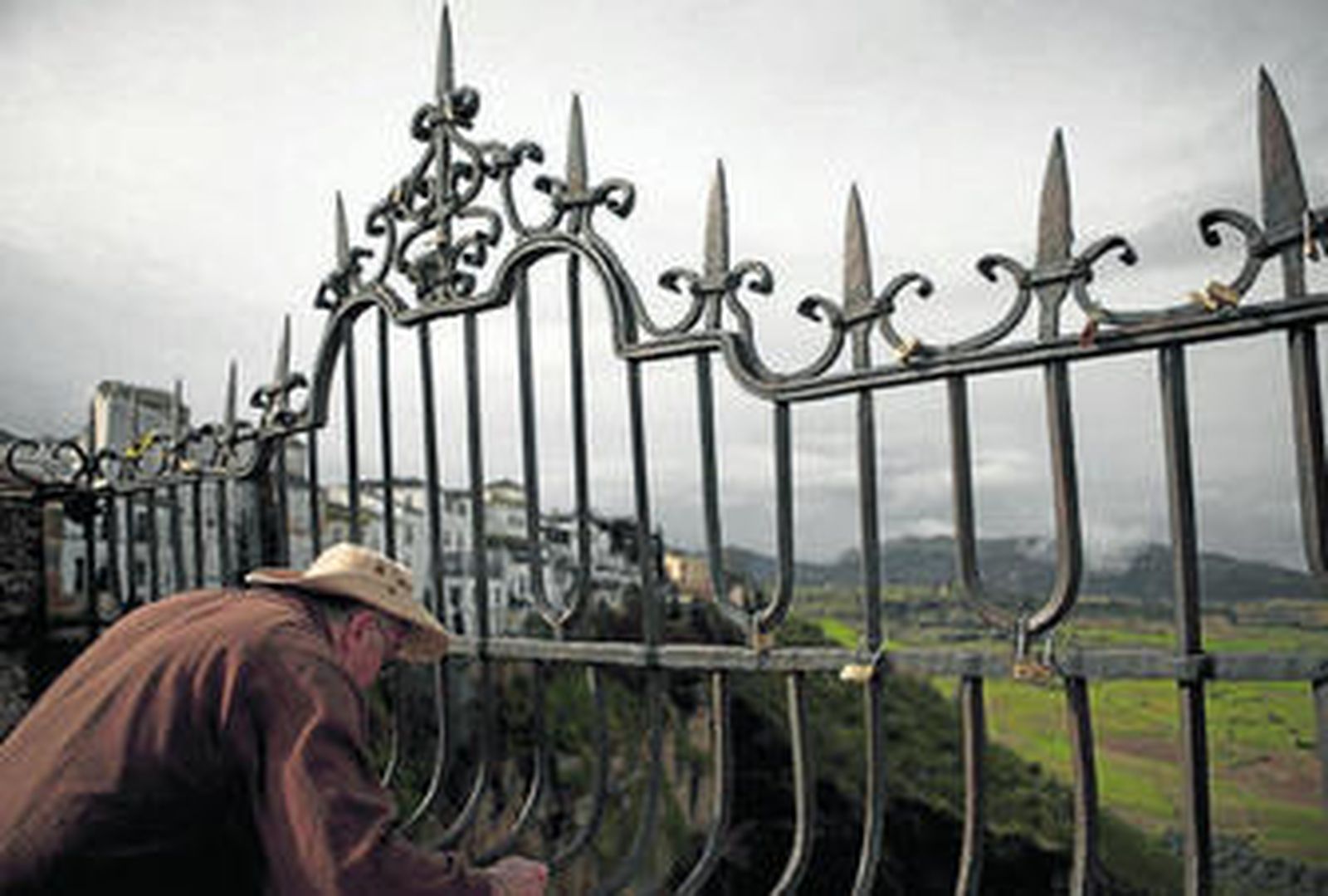 Un turista observa de cerca algunos de los candados colgados del puente.