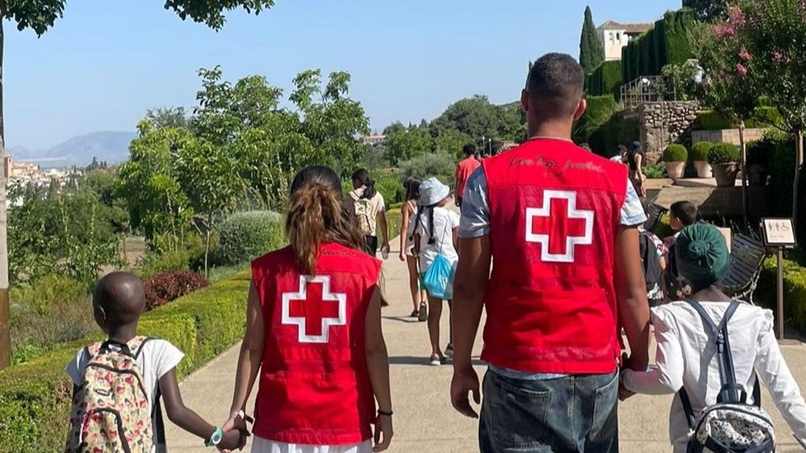 Voluntarios de Cruz Roja paseando junto a niños por la Alhambra