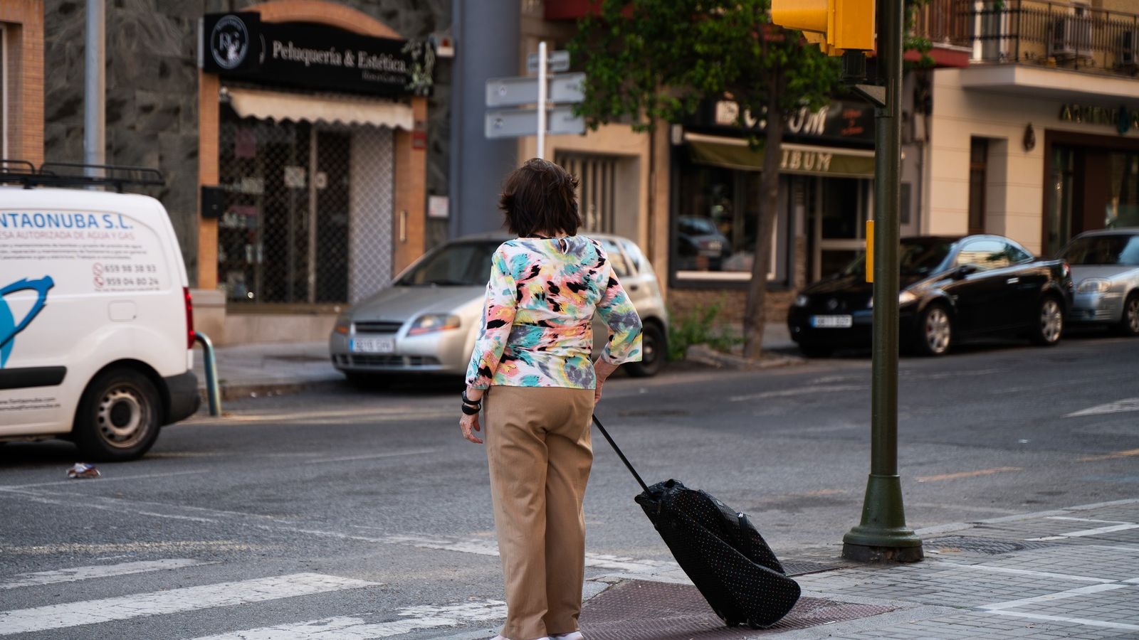 Una mujer con una maleta en un paso de peatones en Huelva.