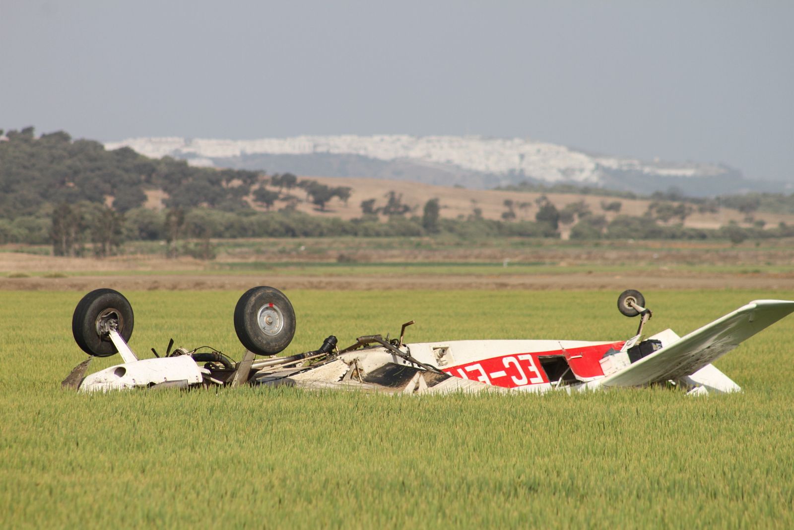 En primer plano, la avioneta siniestrada en la finca barbateña de Los Derramaderos; al fondo, la silueta de Vejer de la Frontera.