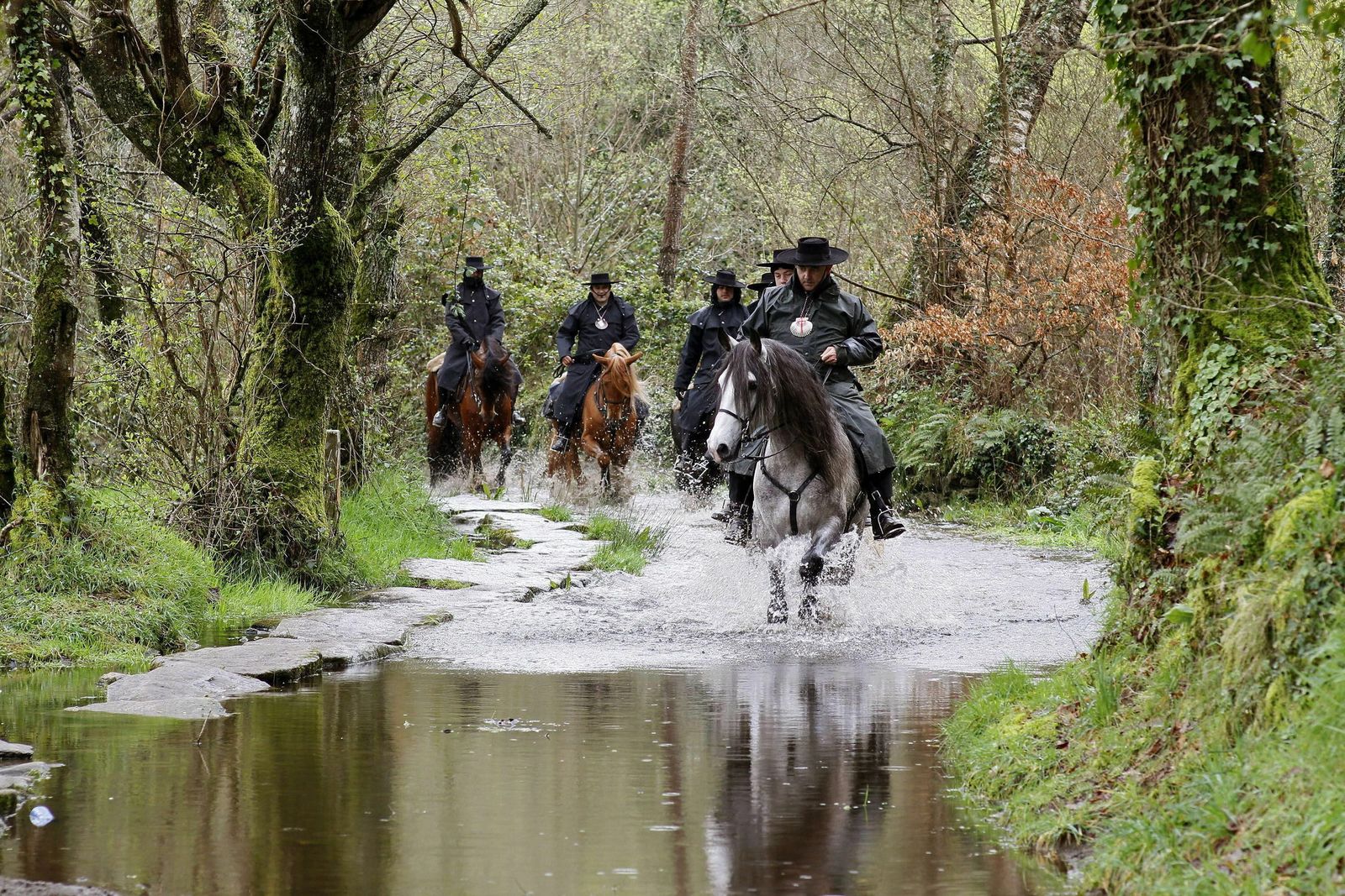 Varios caballistas cruzan un río del Camino Francés