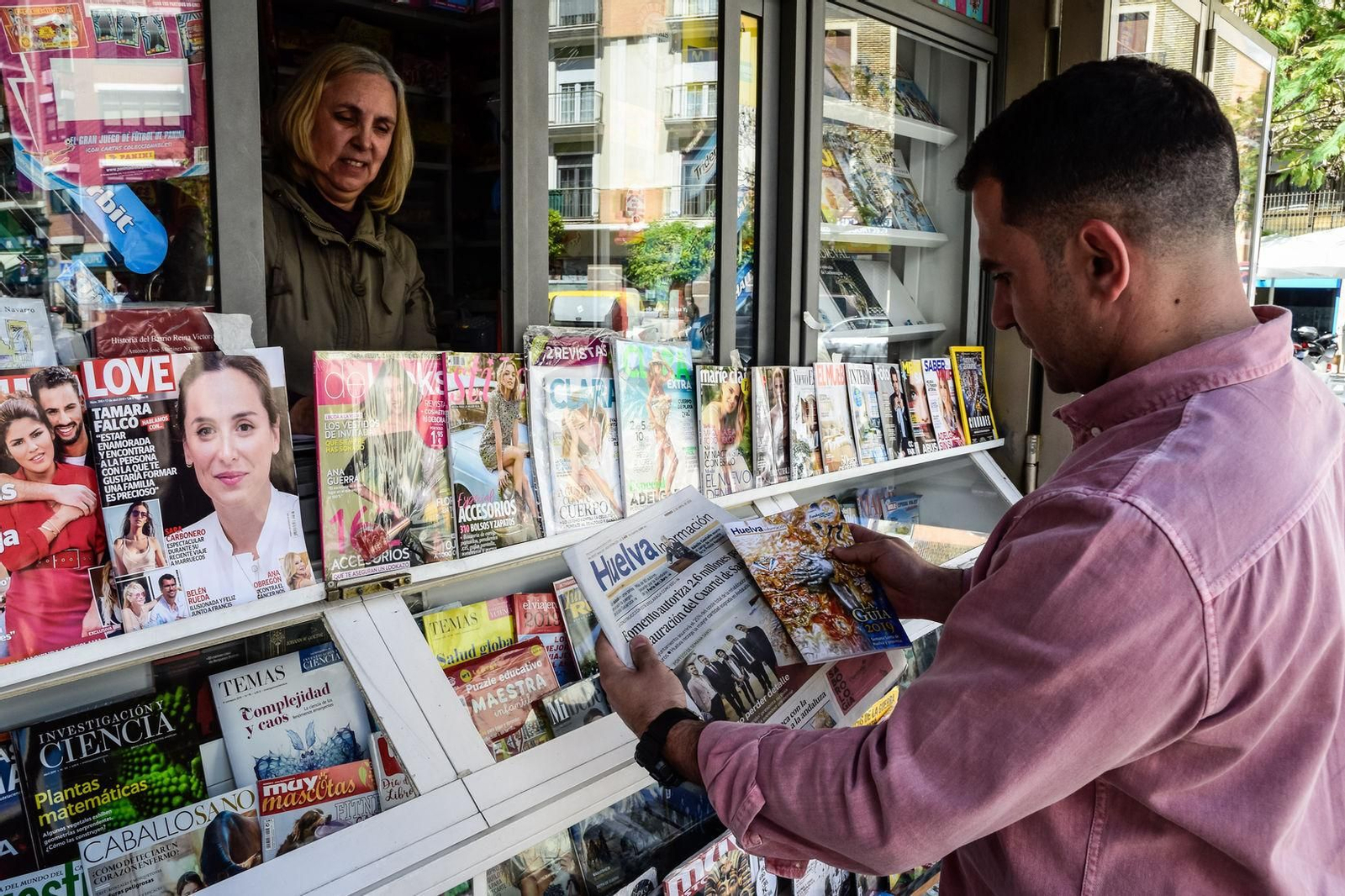 Una persona compra un ejemplar de 'Huelva Información' en un quiosco.