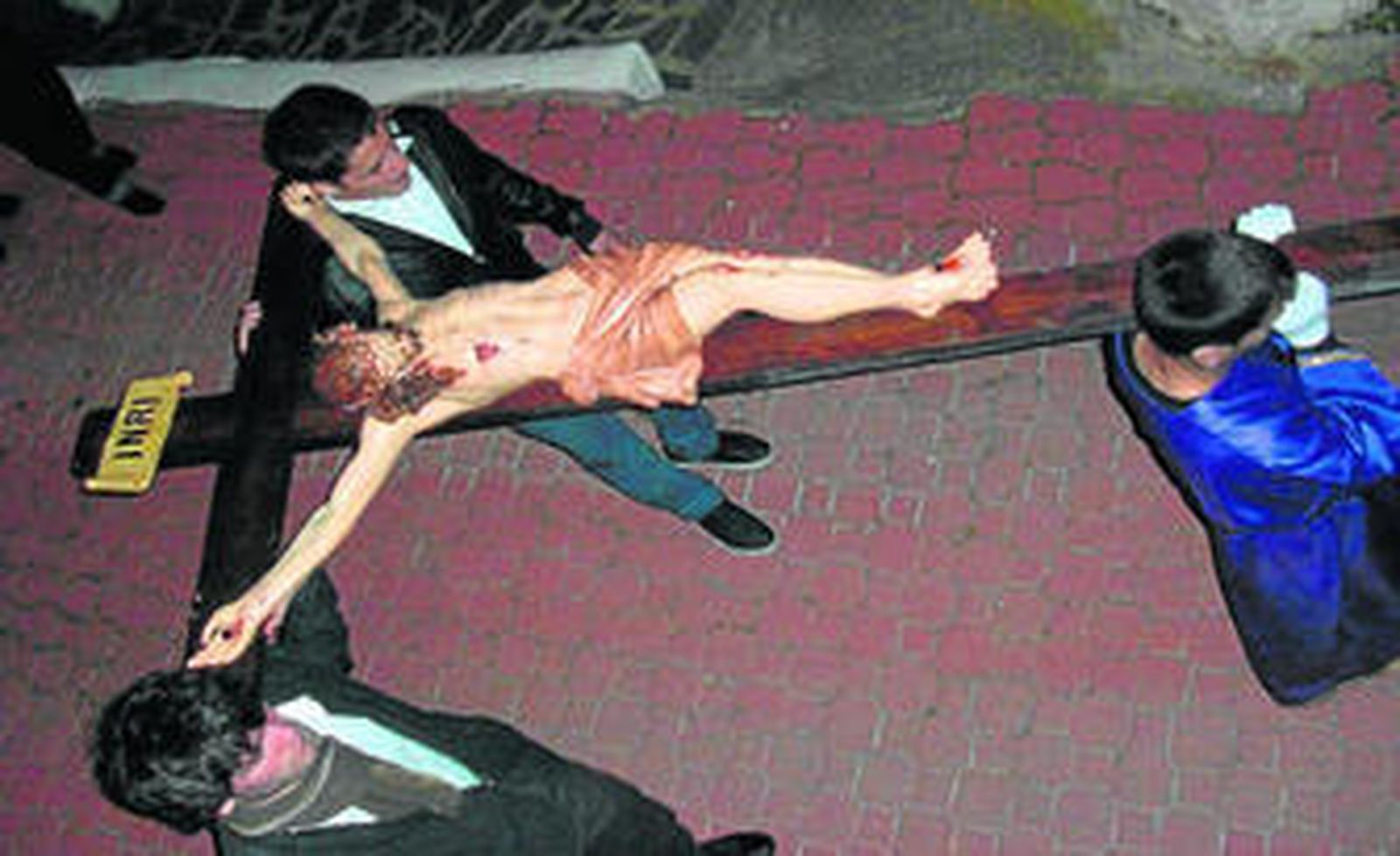 La talla del Crucificado es portada por tres personas.