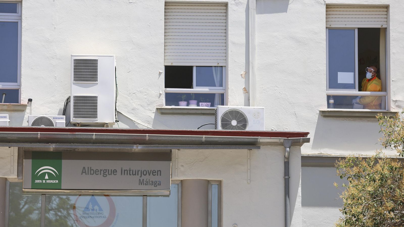 Una persona con mascarilla asomada al albergue de Carranque.