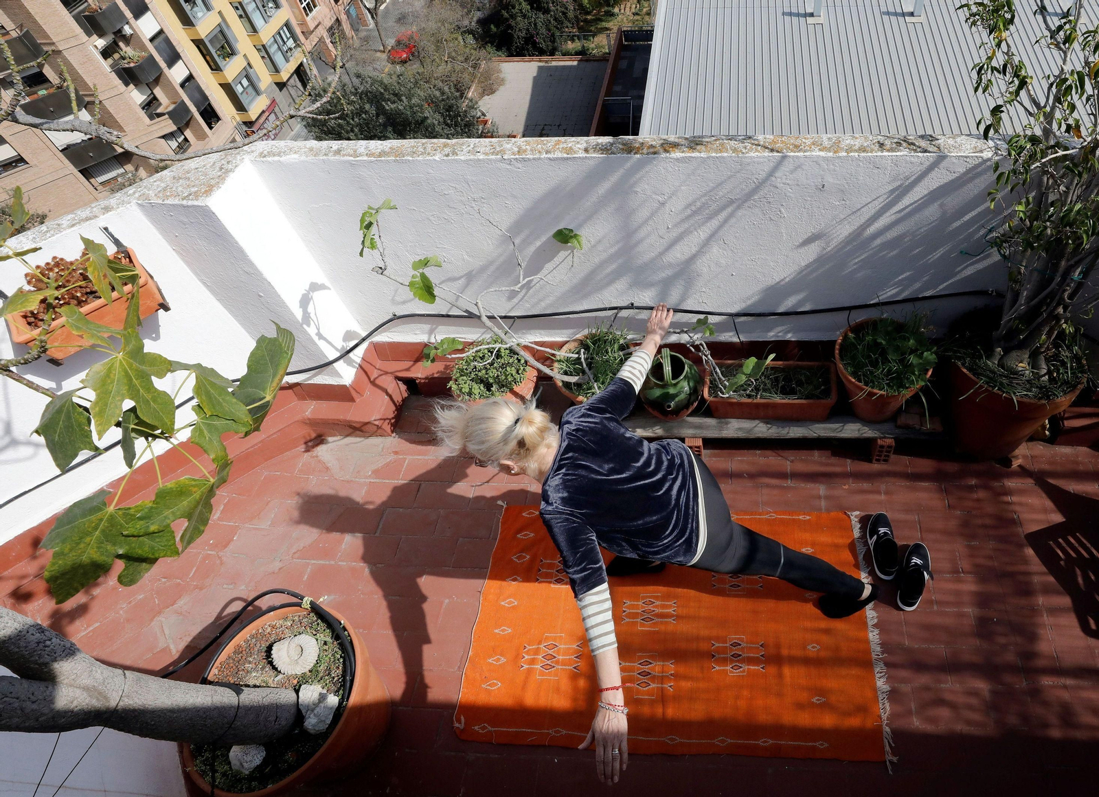 Una mujer hace ejercicio en el balcón de su casa.
