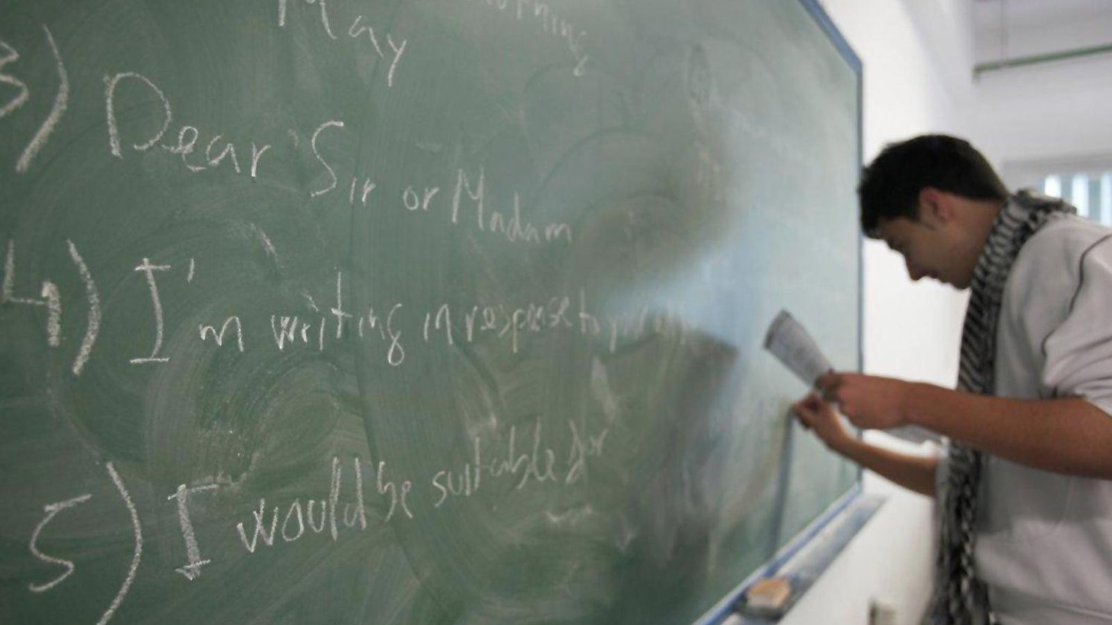 Un alumno escribe en la pizarra frases en inglés.