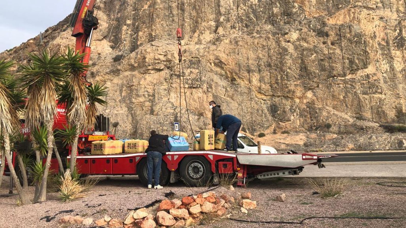 Los agentes colocan los fardos en el camión grúa.
