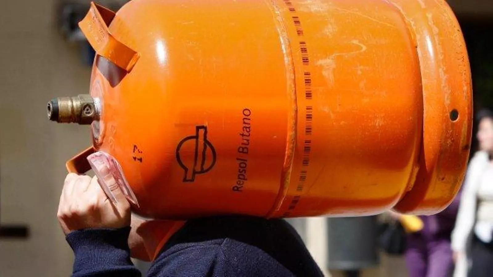 Un trabajador, con una bombona de butano.