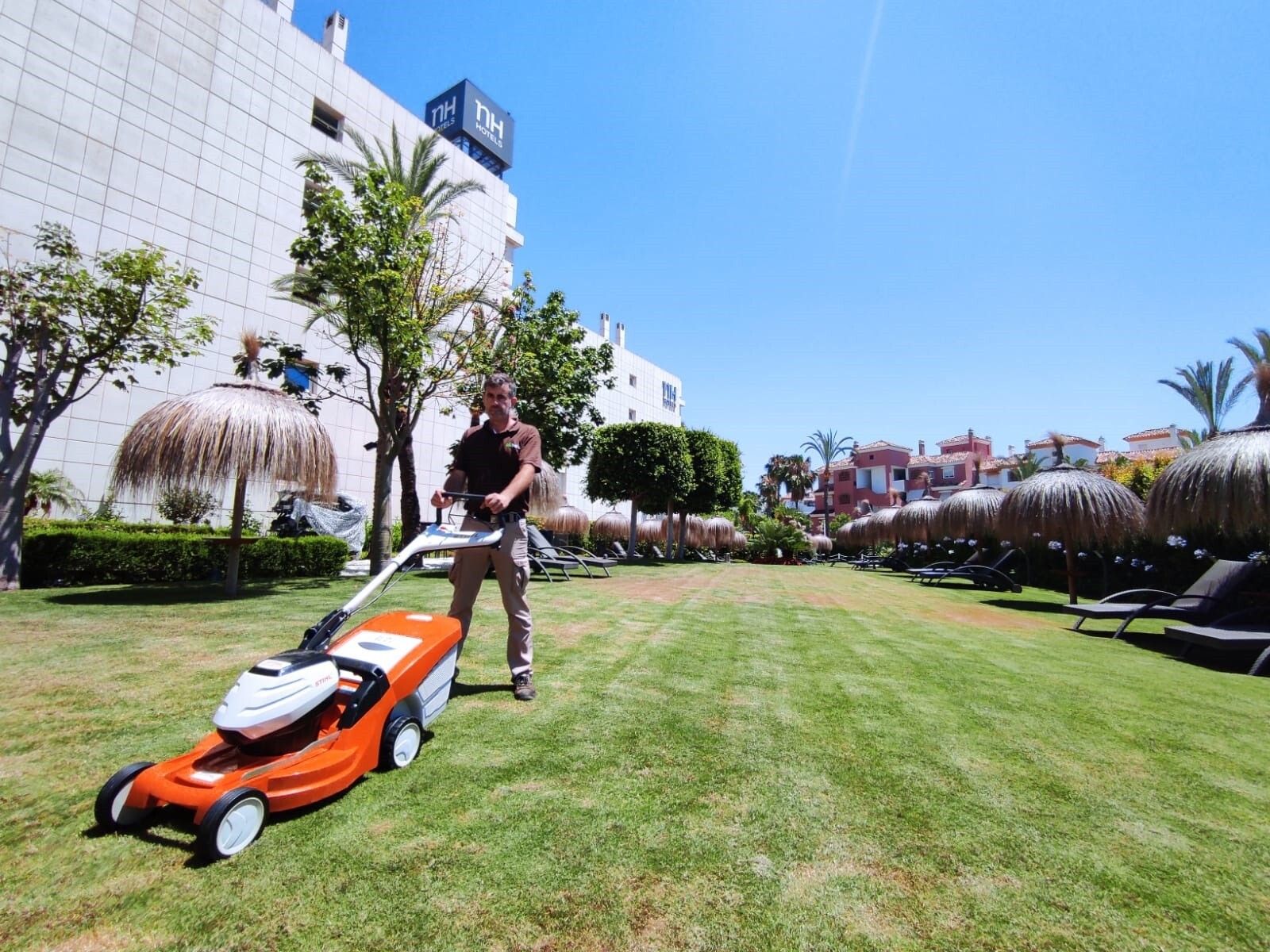 Labores de jardinería en la zona de piscina de un hotel.