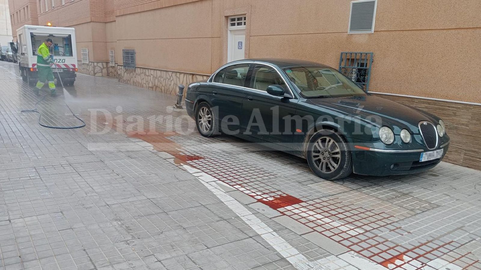 Un operario limpia con una manguera la sangre a escasos metros del escenario del crimen