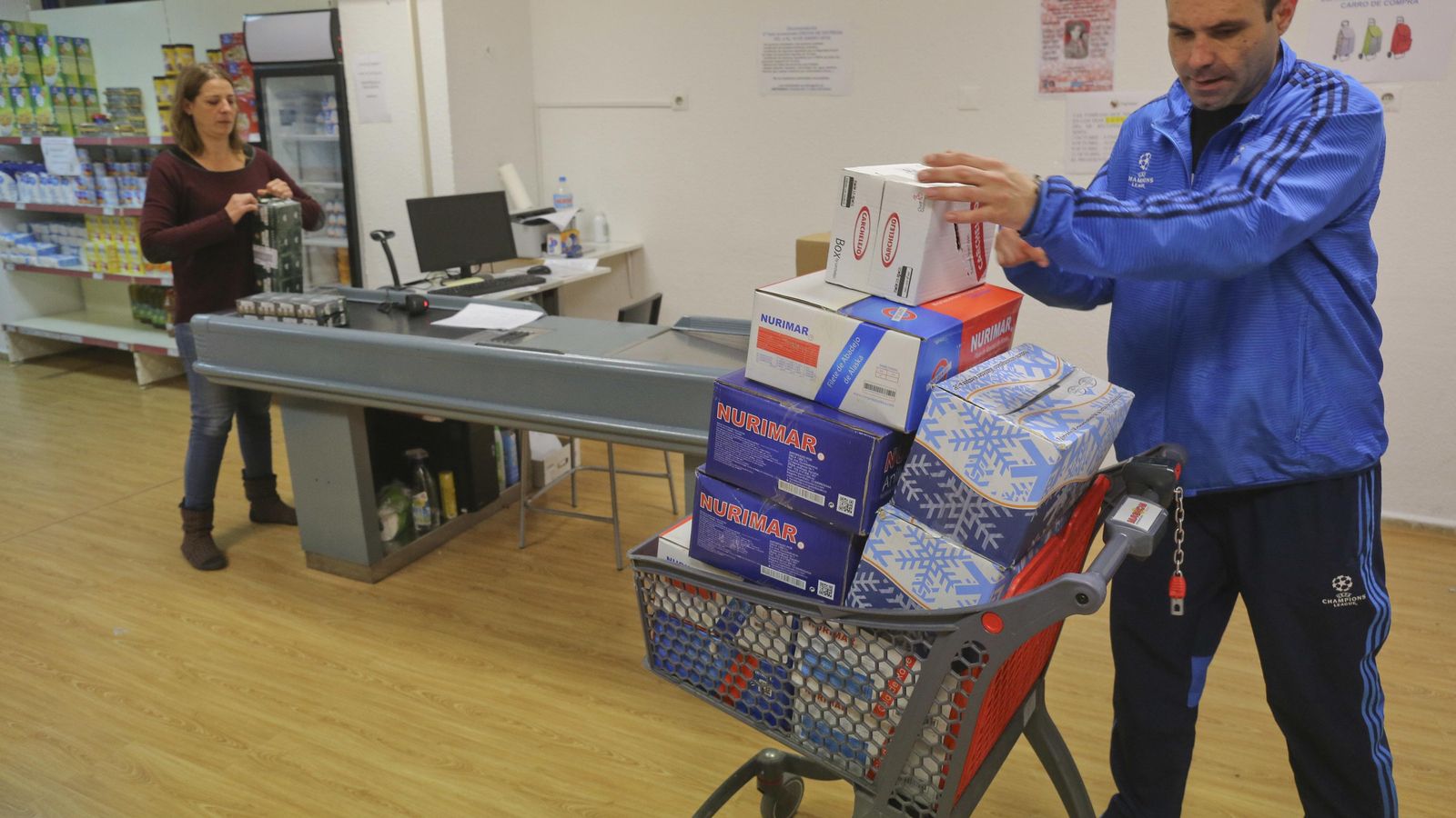 Sonia Luque y un voluntario abastecen el economato.