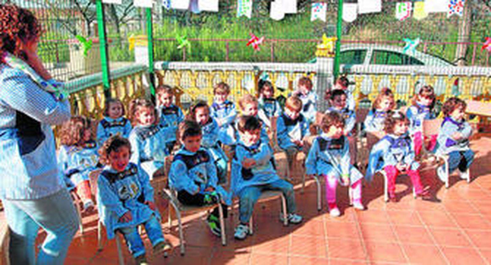 Los niños, en sus sillas, atentos a un mayor que lee un cuento.