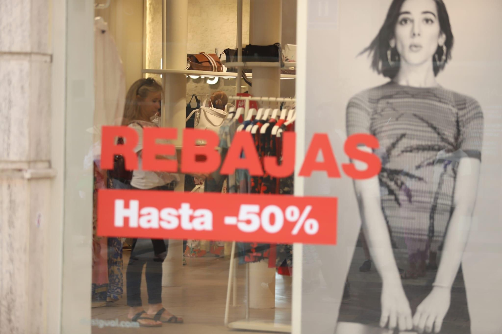 Una mujer obseva ropa en un establecimiento con rebajas en el centro de Málaga Una mujer obseva ropa en un establecimiento con rebajas en el centro de Málaga