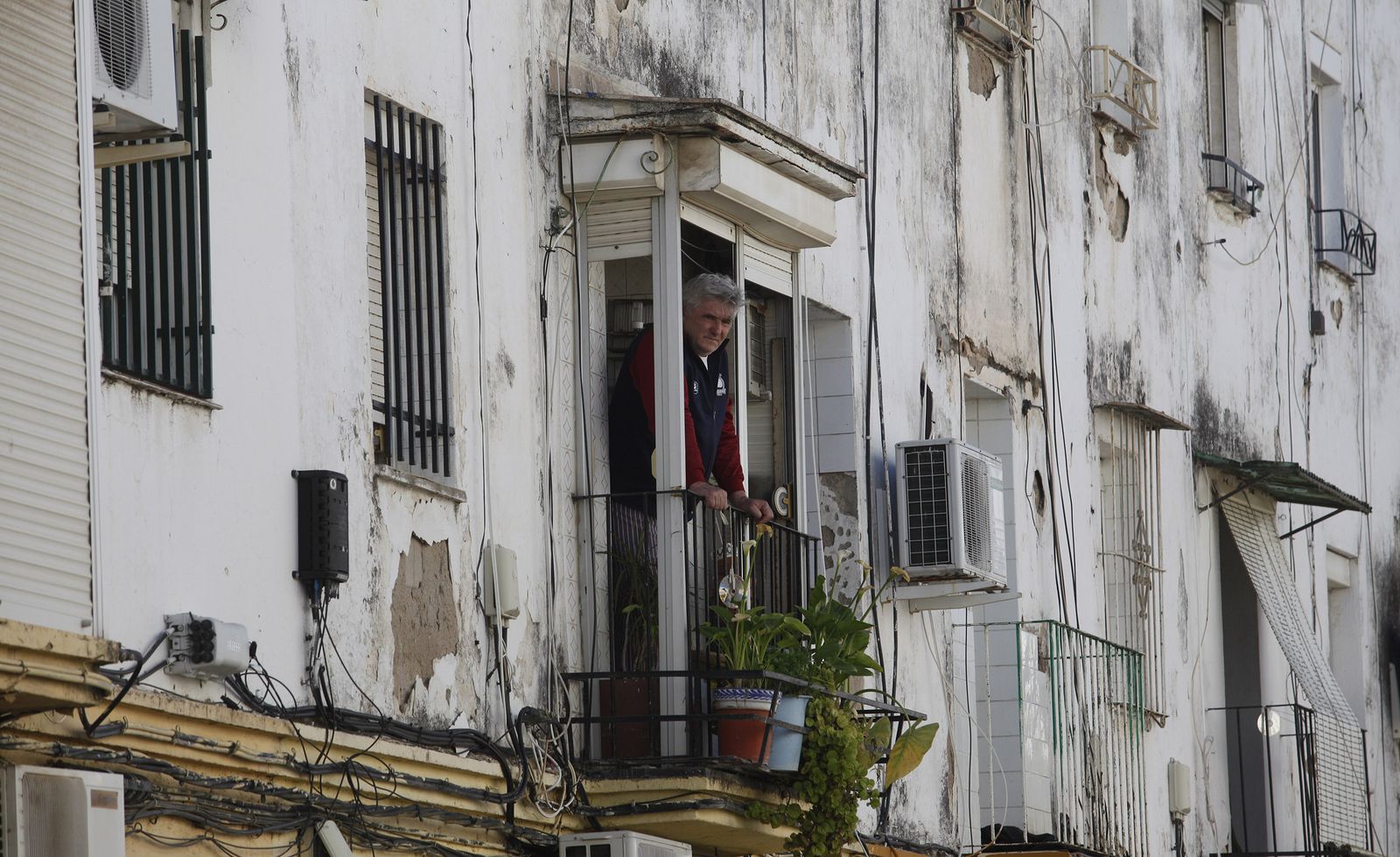 Un hombre observa desde el balcón de su casa el trabajo de la Policía, el pasado 3 de abril, cuando fue asesinada una mujer en la calle Perdiz.