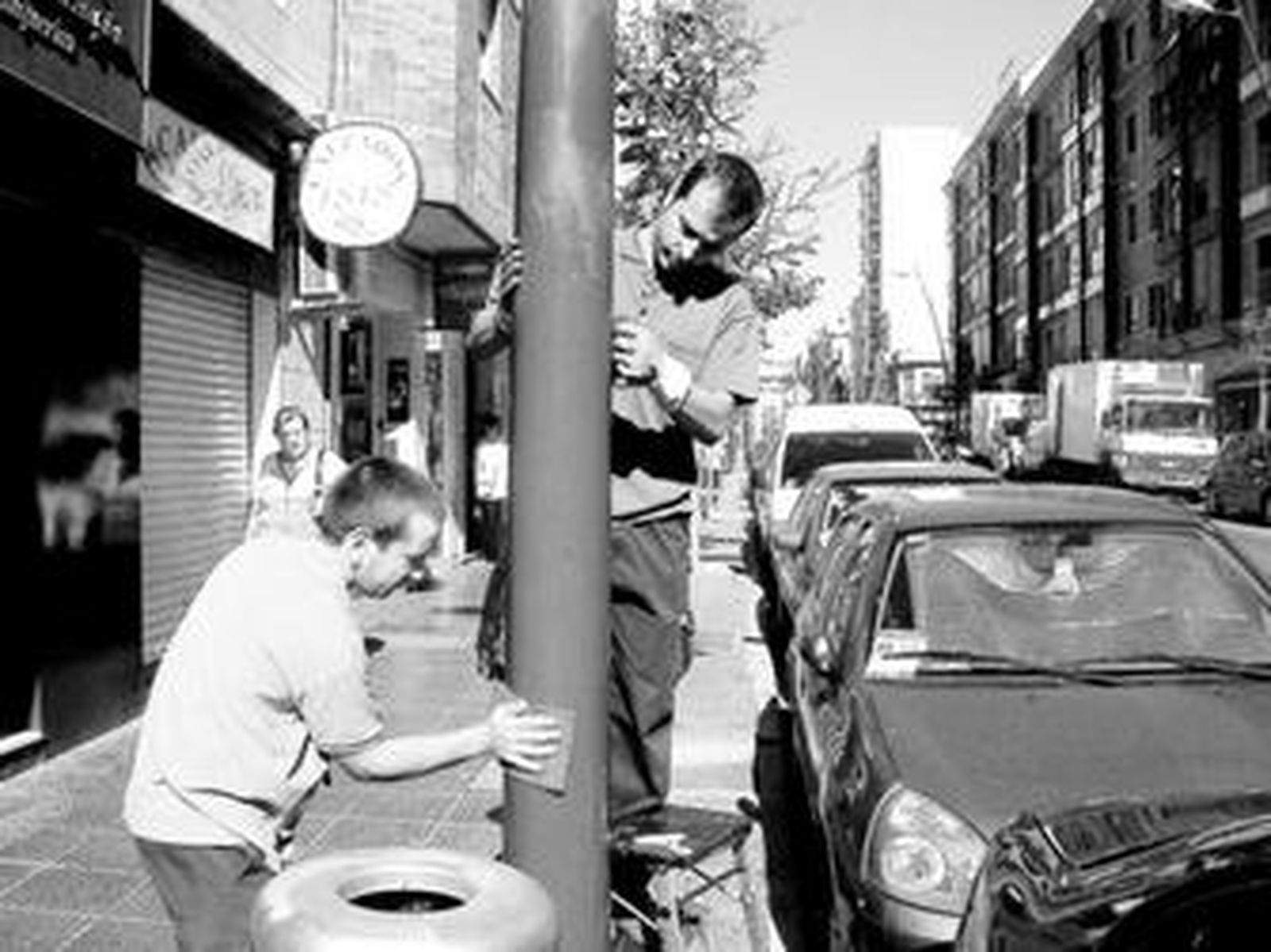 Dos operarios 'asean'  un semáforo de anuncios publicitarios.