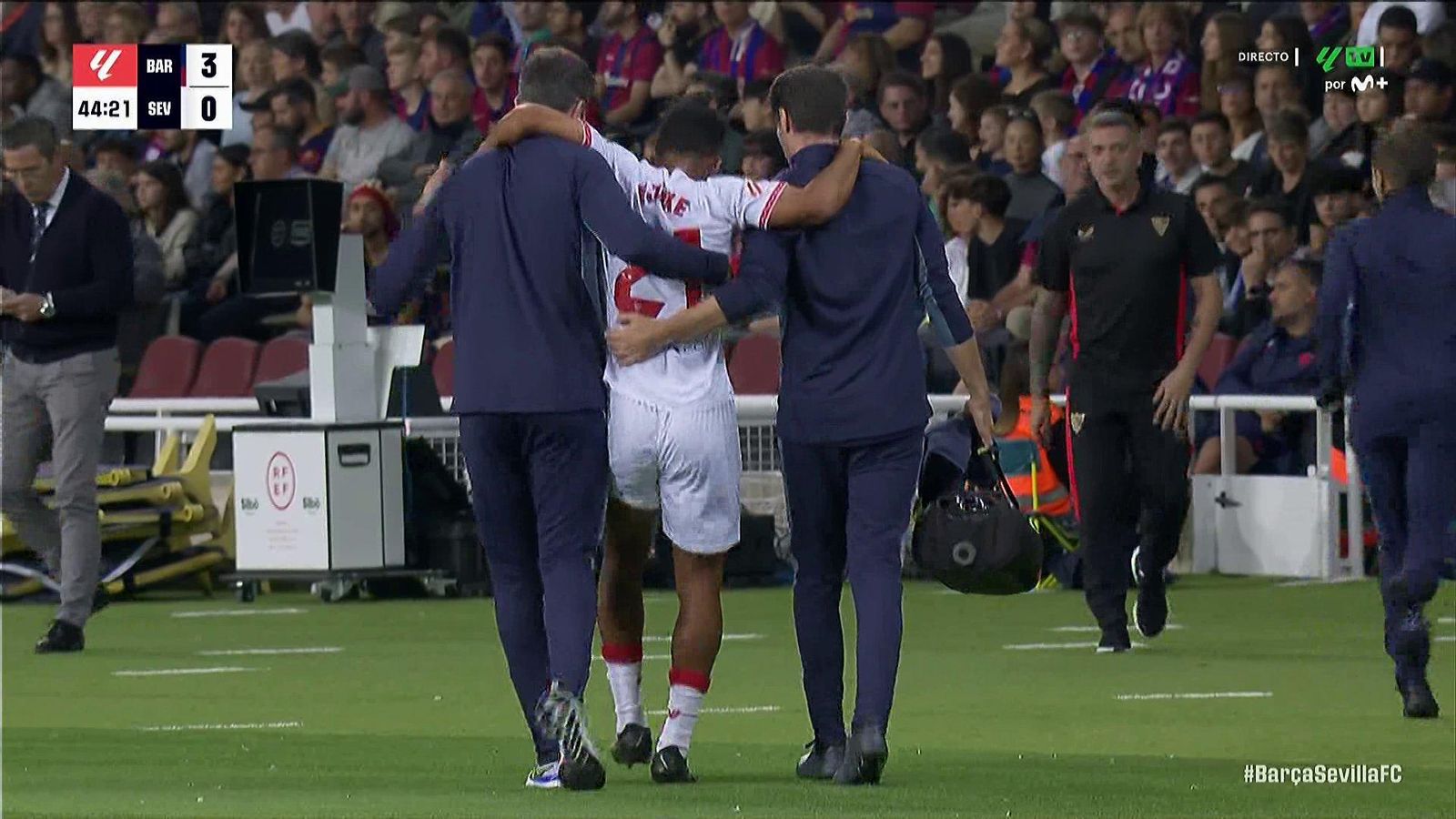 Ejuke, ayudado por los servicios médicos del Sevilla, abandona el partido ante el FC Barcelona.