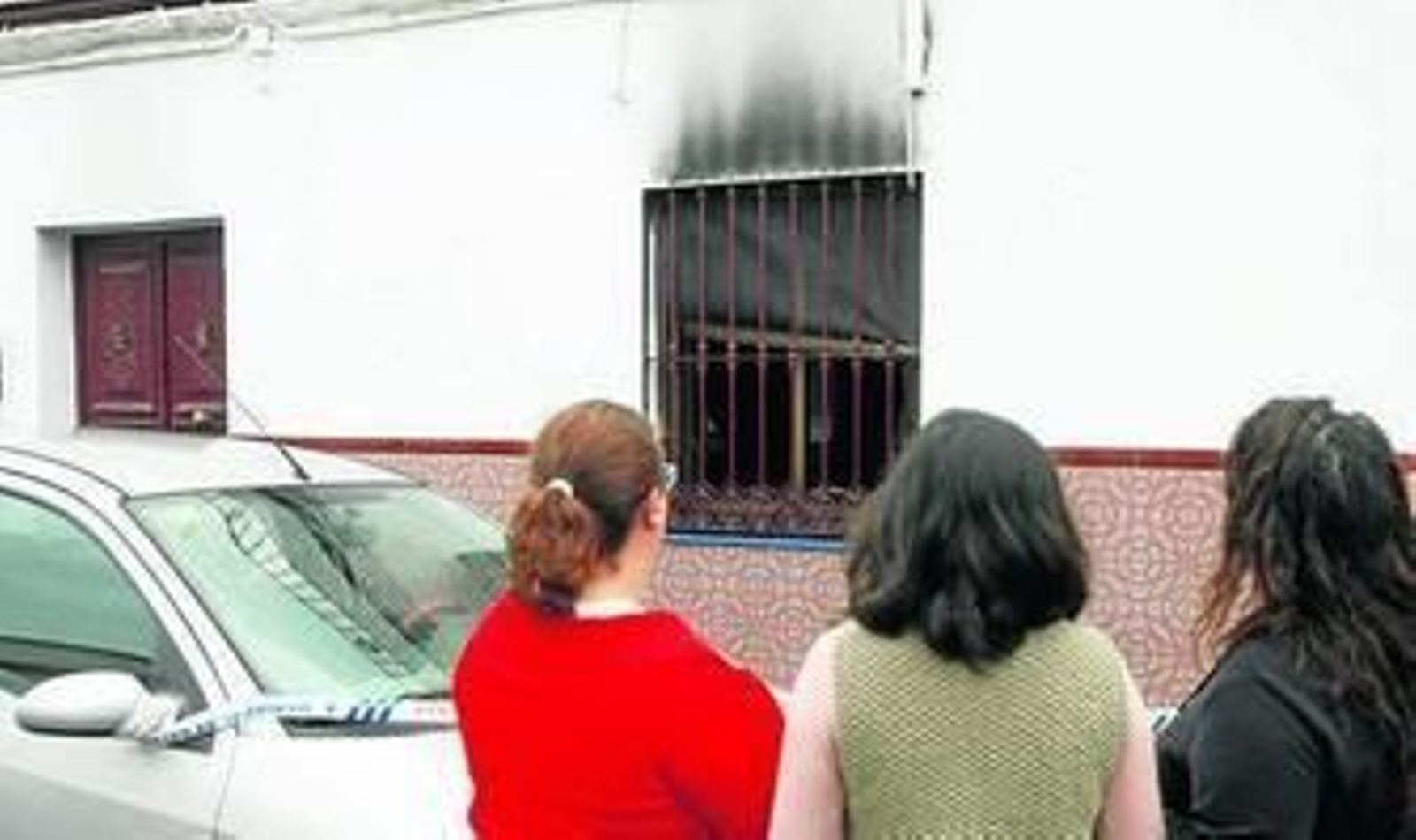 Tres mujeres contemplan la casa incendiada, ayer en Alcalá.