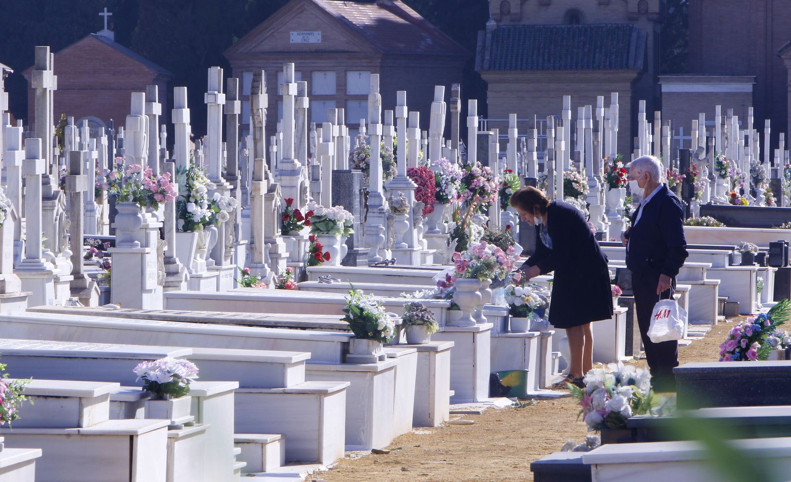 Dos personas depositan flores en una tumba en el cementerio San Fernando de Sevilla.