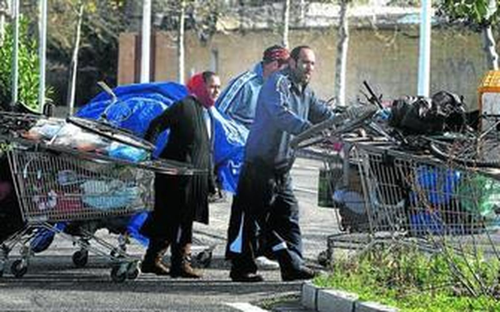 Un grupo de indigentes trasladan en carros de supermercado residuos depositados dentro y fuera de los contenedores.