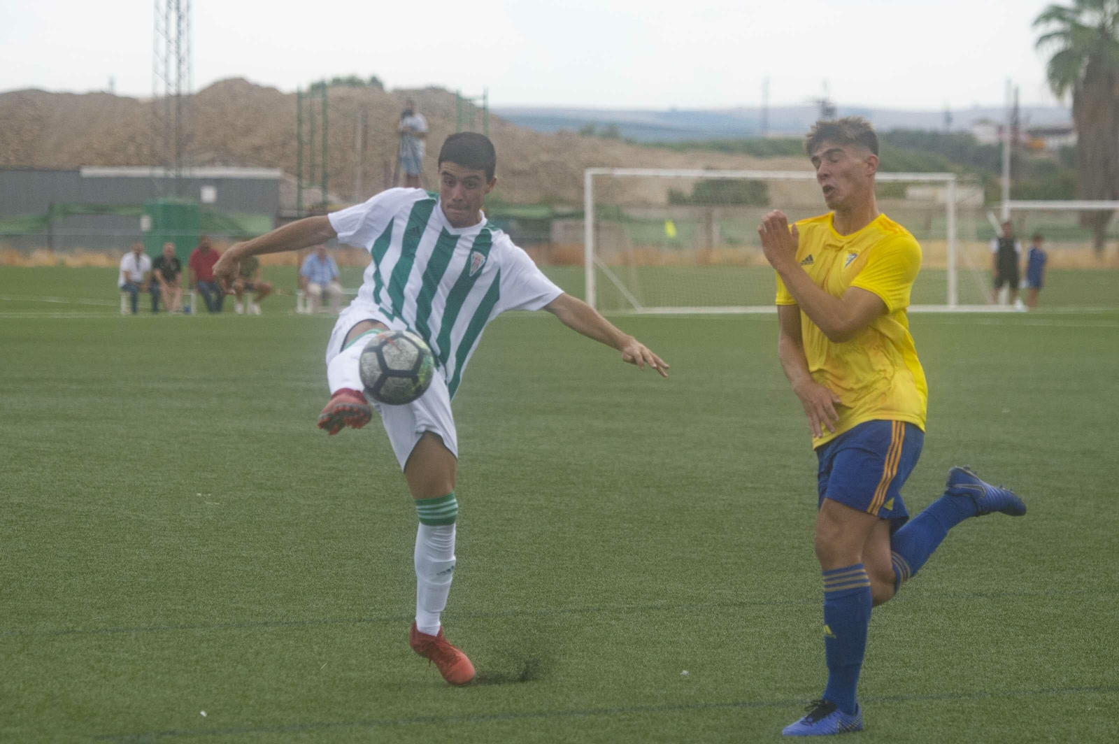 Un jugador del Córdoba intenta centrar con la oposición de un jugador del Cádiz.