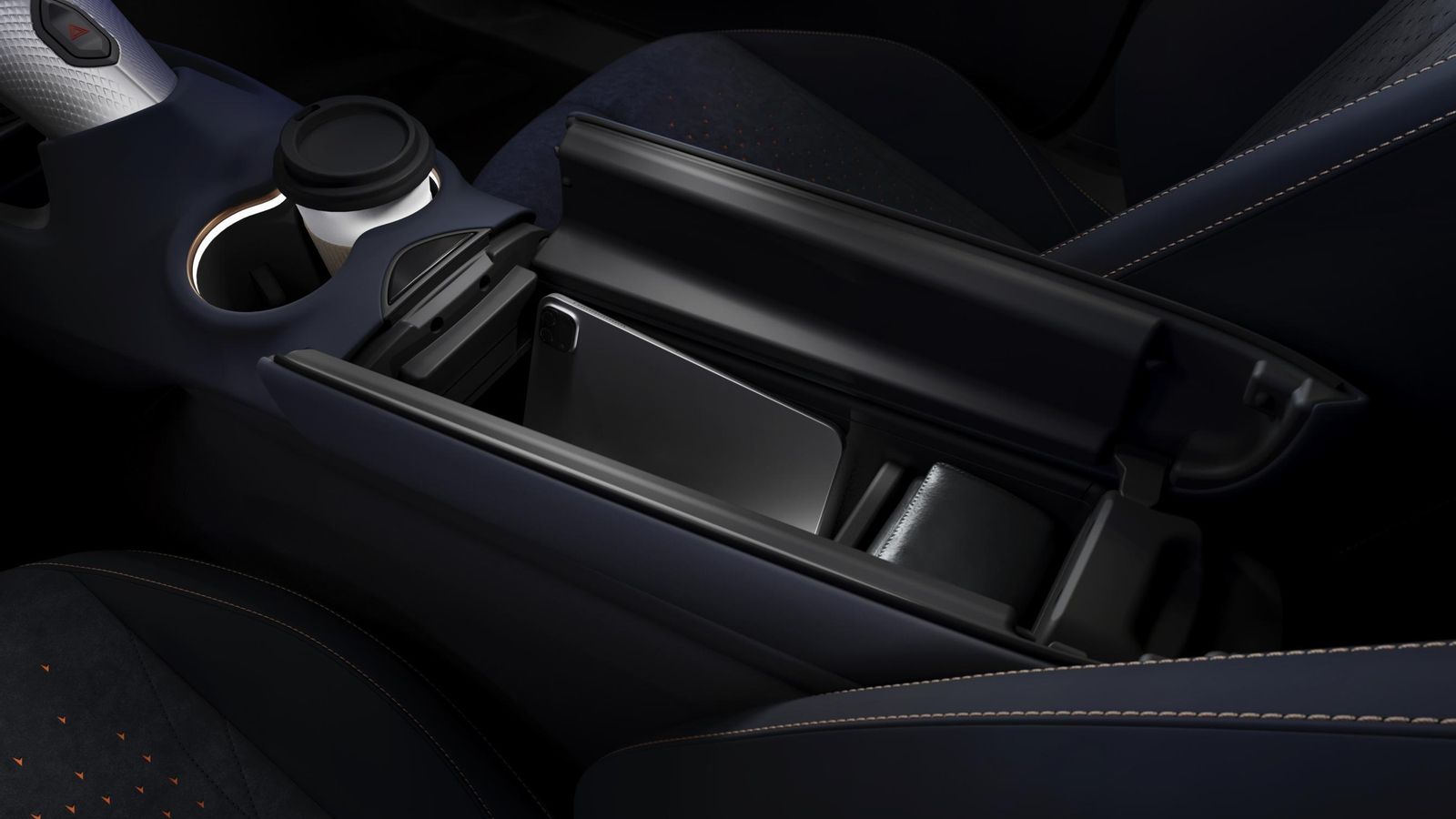 Entre los dos asientos, además de los reposavasos iluminados, hay un hueco amplio e iluminado bajo el apoyacodos de apertura en mariposa.