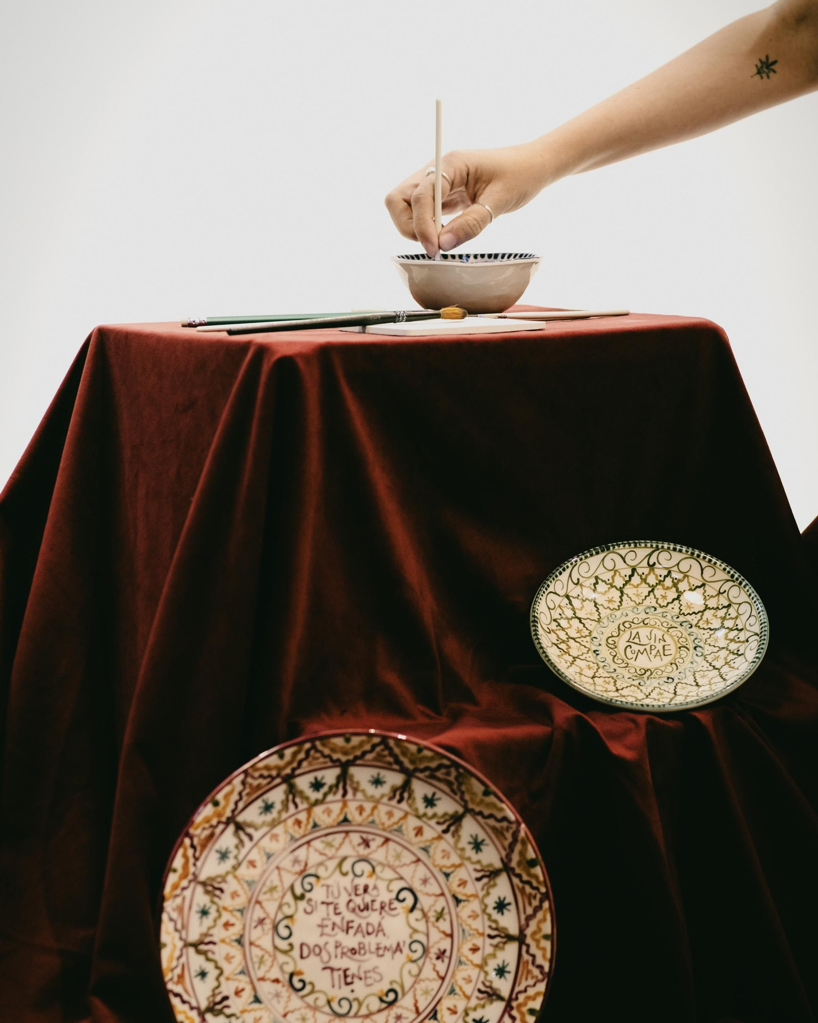 La artista hunde el pincel en pintura mientras trabaja en una de sus piezas.