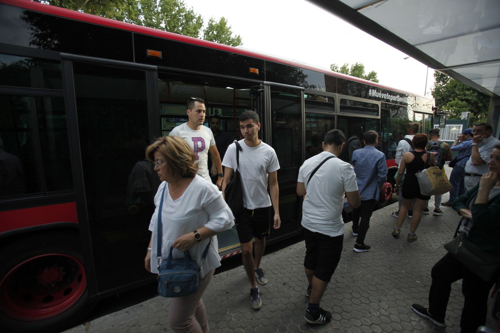 Varios usuarios de Tussam suben y bajan de un autobús.