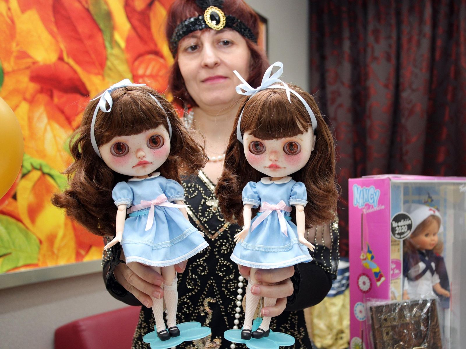 Una mujer posa con dos de las famosas muñecas.