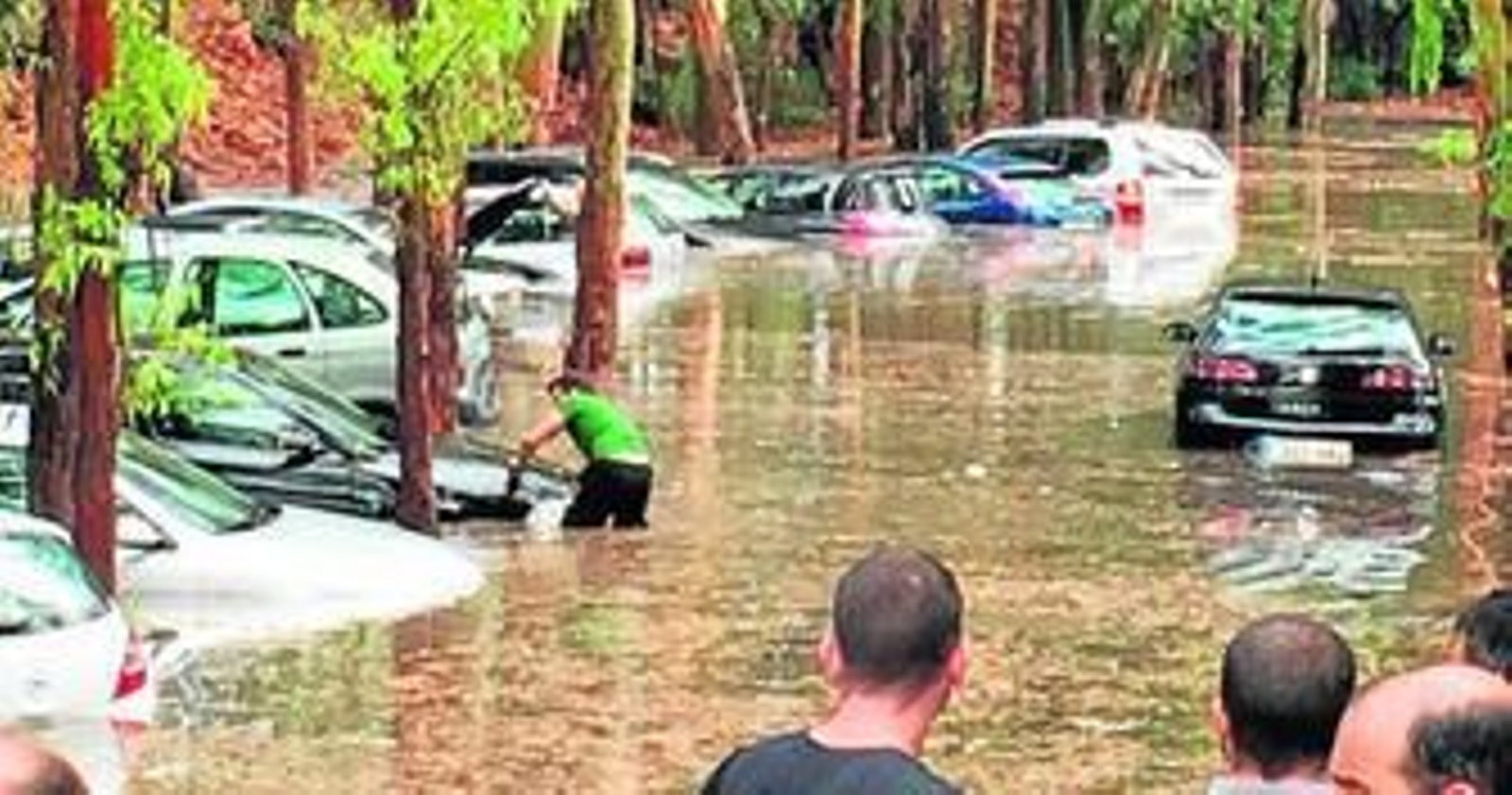 Trabajadores de un concesionario, ayer, tratando de sacar sus vehículos sumergidos en un descampado cerca del aeropuerto.