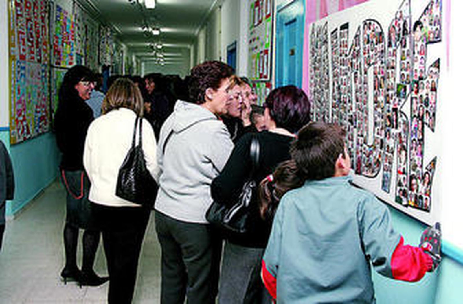Padres y alumnos contemplan el tablón de un centro.