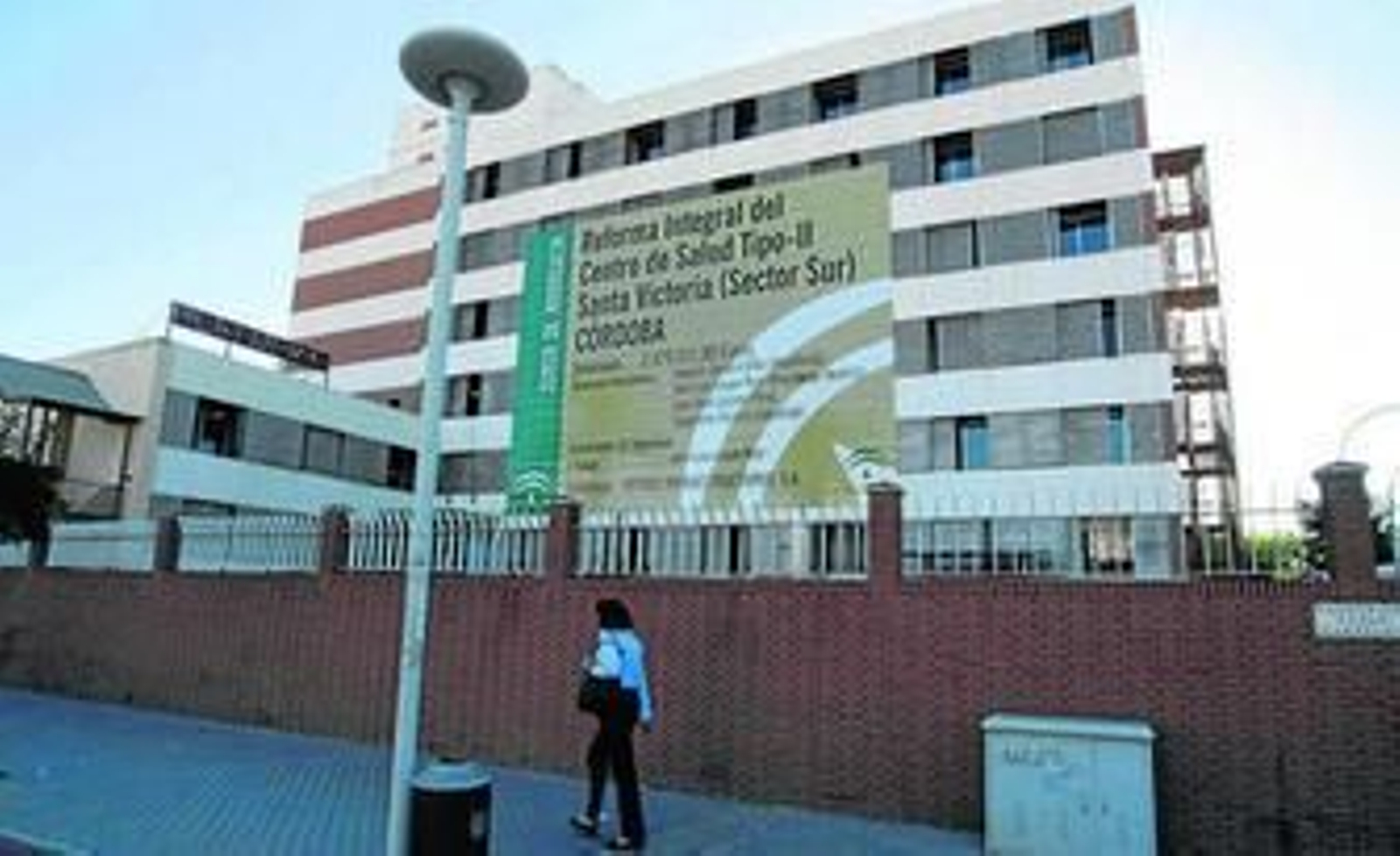 Una ciudadana pasa delante del cartel de las obras del centro de salud del Sector Sur.